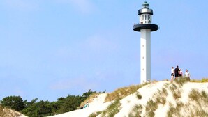 A lighthouse on a sandy hill with a clear sky. - 2 Person Holiday Home in Nexo (Nexø)