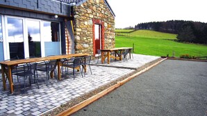 A stone building with a red door, a wooden table, and chairs outside. - Lovely House With Much Luxury and Comfort (Waimes)