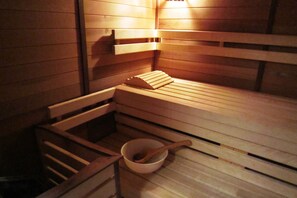 Eine Holzsauna mit Bänken und einer Holzkugel mit Löffel.