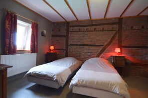 A bedroom with two beds, a window with curtains, a radiator, and a brick wall. - Lovely House With Much Luxury and Comfort (Waimes)
