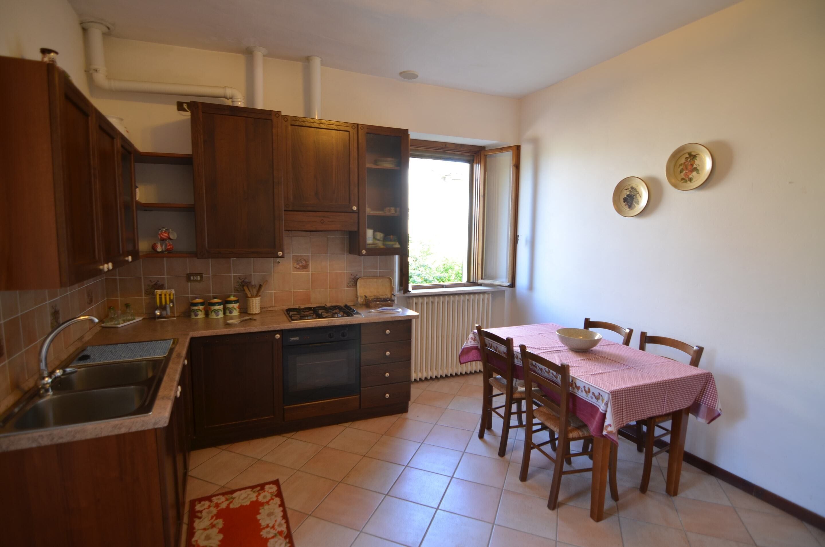 Una cocina con armarios de madera, un fregadero, una estufa y una mesa de comedor con sillas.