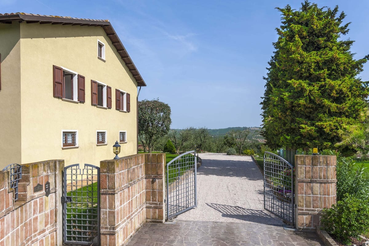 A gated entrance to a building with a stone pathway leading to a gravel driveway.