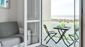 A balcony with a view of the ocean, a grey sofa, and a table with chairs. - Amazing Holiday Home Near Pet-friendly Beach (Carrara)