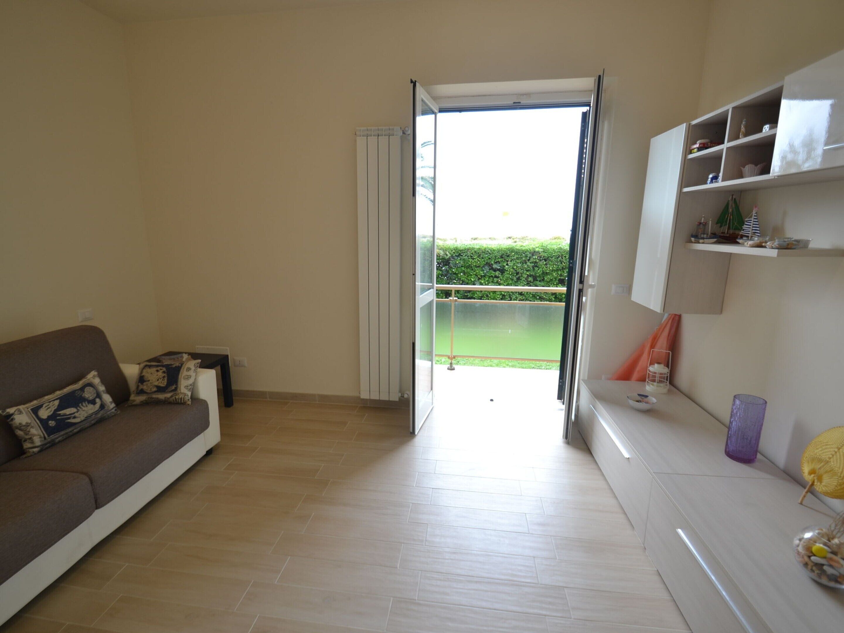 A living room with a brown sofa, a white cabinet, and a glass door leading to a balcony.