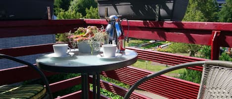 A balcony with a table, chairs, and potted plants.