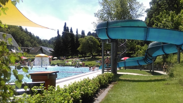Una piscina con tobogán y fuente.