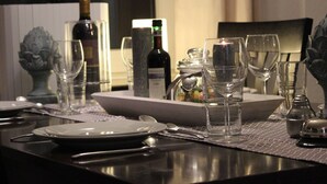 Una mesa puesta con platos, cubiertos, vasos y una botella de vino.