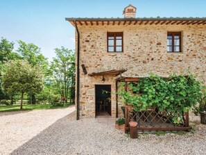 A stone building with a gravel driveway and a vine-covered pergola. - Scenic Apartment in Casole D'elsa With Pool (Casole d'Elsa)