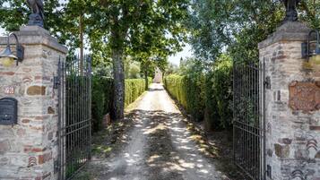 A pathway leading to a gated area with stone walls, metal gates, and a statue.
