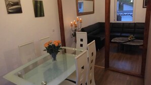 A dining area with a glass table and chairs, a vase of flowers, and a black sofa in the background. - Comfortable Holiday Home Near Vineyards in Bremm (Bremm)