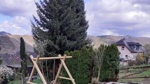 A garden with a wooden swing set, a concrete planter with flowers, and a paved path. - Comfortable Holiday Home Near Vineyards in Bremm (Bremm)