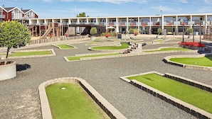 Une cour avec un espace de jeux pour enfants, un bâtiment doté de nombreux balcons et un ciel dégagé.