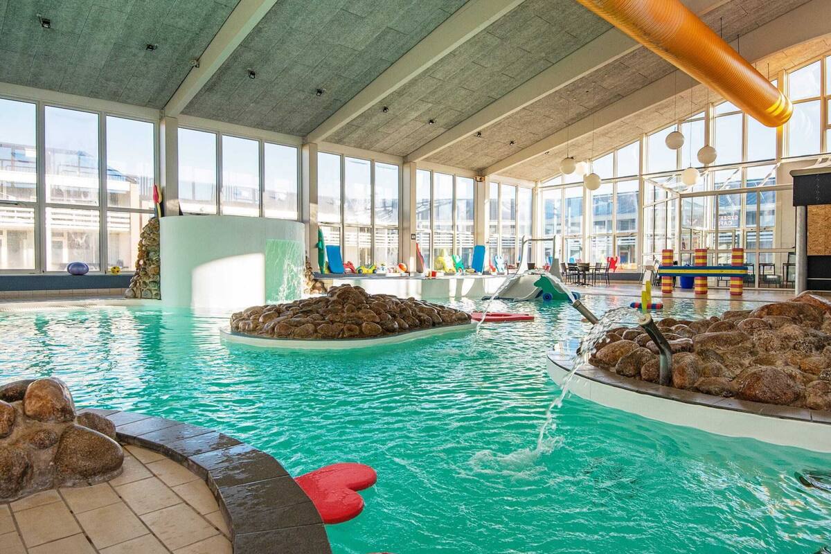 Une piscine intérieure à l’eau claire, agrémentée de formations rocheuses et d’éléments de jeu colorés.