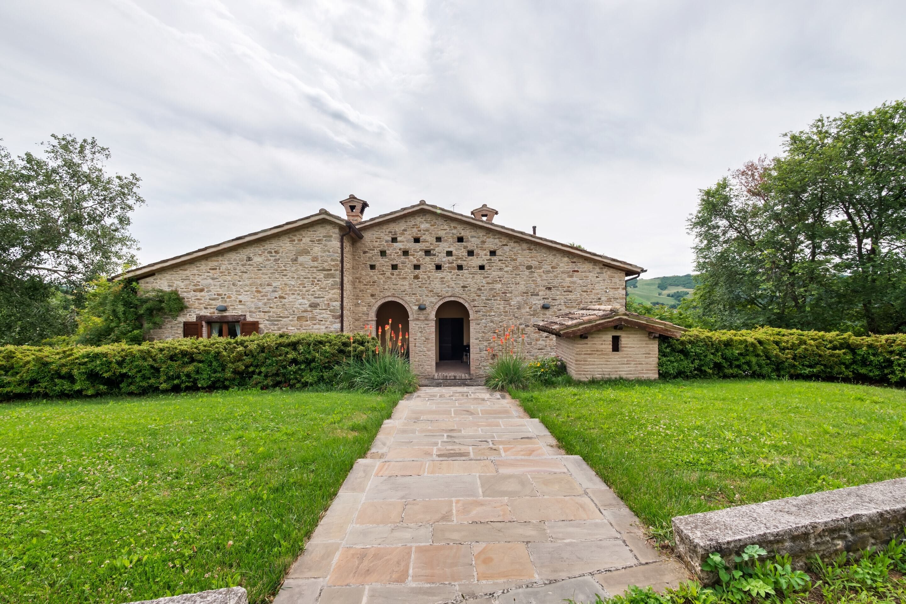 A stone building with a central entrance, surrounded by a well-maintained lawn and hedges.