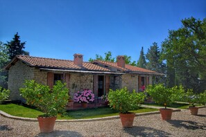 Una casa in pietra con tetto in tegole, circondata da ghiaia e piante in vaso.