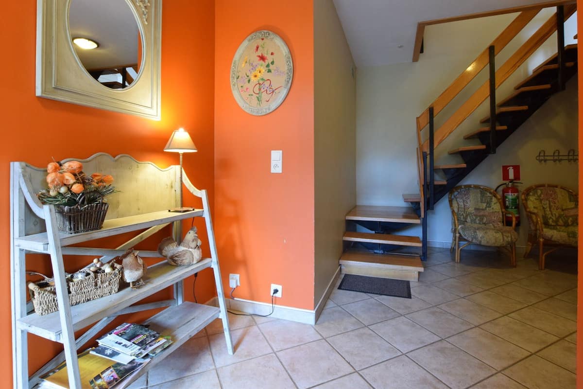 A living room with a staircase, a bench, and a wall-mounted mirror.