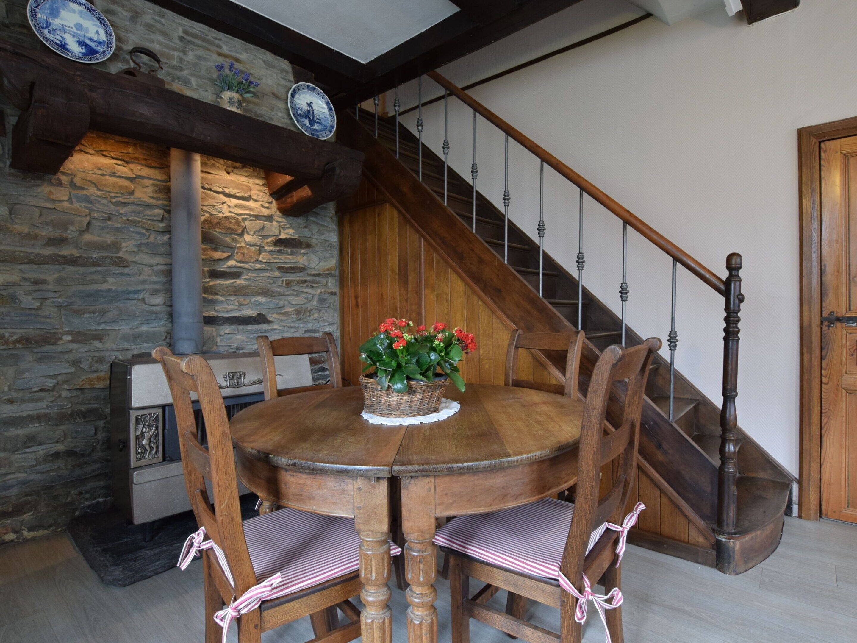 A dining area with a stone wall, wooden staircase, and a table with chairs.