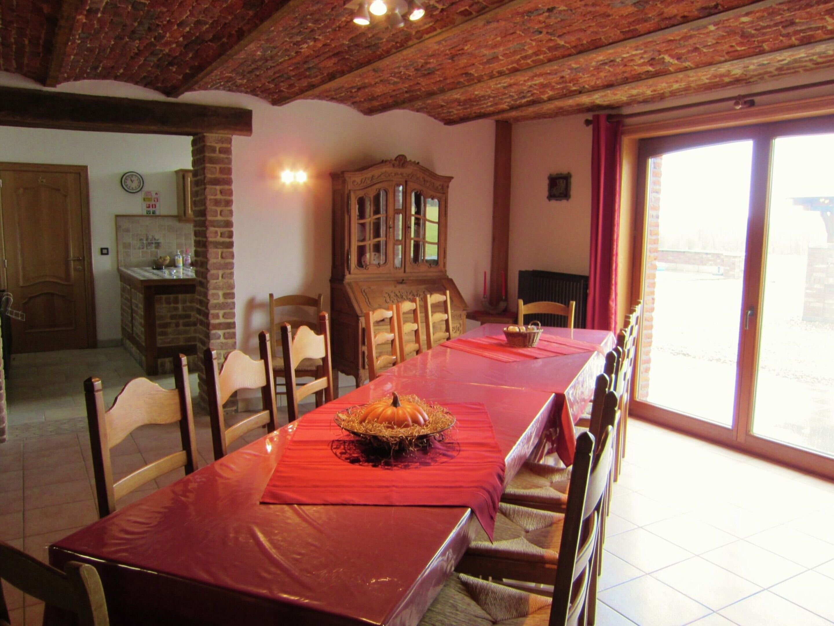 Ein Esszimmer mit einem langen Tisch, Holzstühlen, einem Holzschrank und Blick durch eine Glastür.