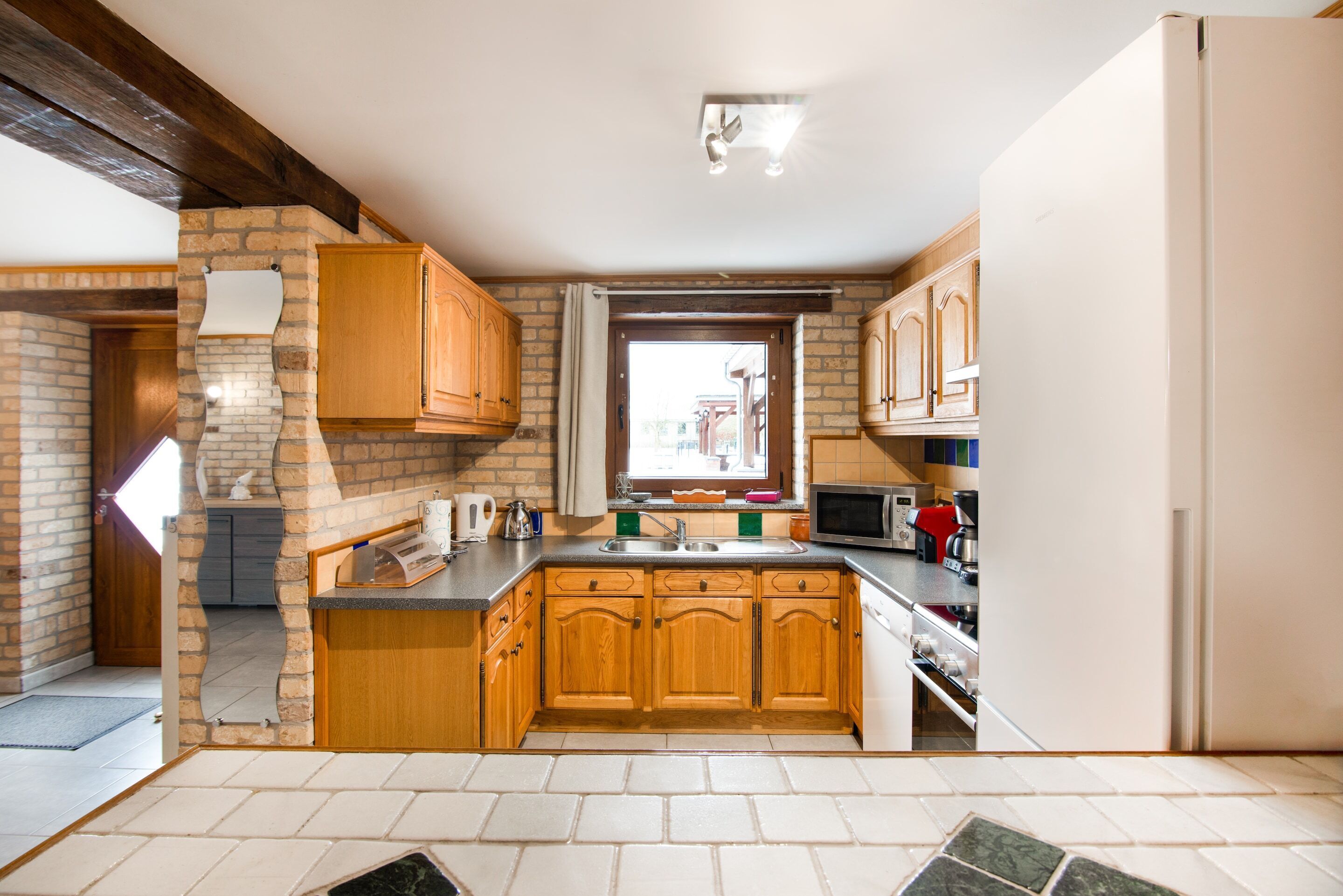 A modern kitchen with wooden cabinets, a built-in oven, and a window with curtains.