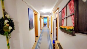 Un couloir étroit avec un tapis à rayures, des portes en bois et un radiateur fixé au mur.