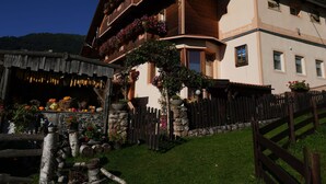 Un chalet traditionnel en bois, avec des fondations en pierre, des balcons en bois ornés de jardinières et une clôture en pierre.