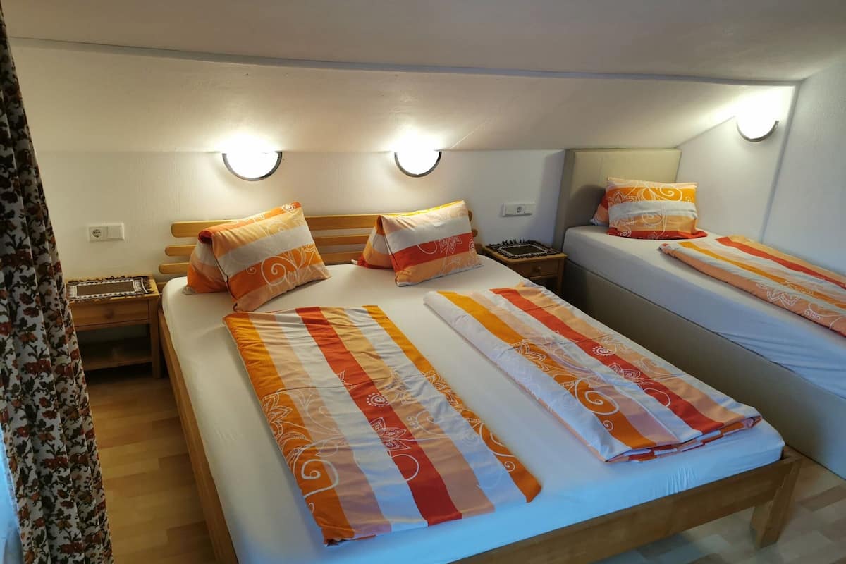 Ein Hotelzimmer mit zwei Betten, jeweils mit gestreifter Bettwäsche und passenden Kissen. An den Nachttischen stehen Lampen und ein kleiner Beistelltisch mit einem Schachbrett.