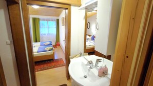Une chambre d’hôtel avec un plafond en bois, un grand miroir, un lavabo blanc et un lit avec une literie bleue.