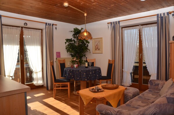 Une pièce chaleureuse avec un plafond en bois, une table à manger avec des chaises, un canapé et une petite table sur laquelle se trouve un bol.