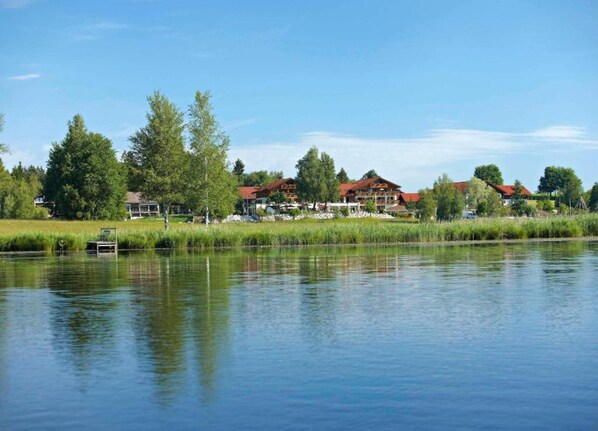 A lakeside property with multiple buildings, a dock, and surrounding greenery.