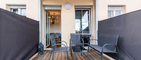 An outdoor patio with a wooden deck, metal chairs, and a table.