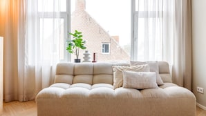Una sala de estar moderna con un sofá color beige, una mesa de centro redonda y una planta en maceta.