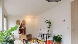 Amplia habitación con zona de juegos que incluye vías de tren de madera y vehículos de juguete.