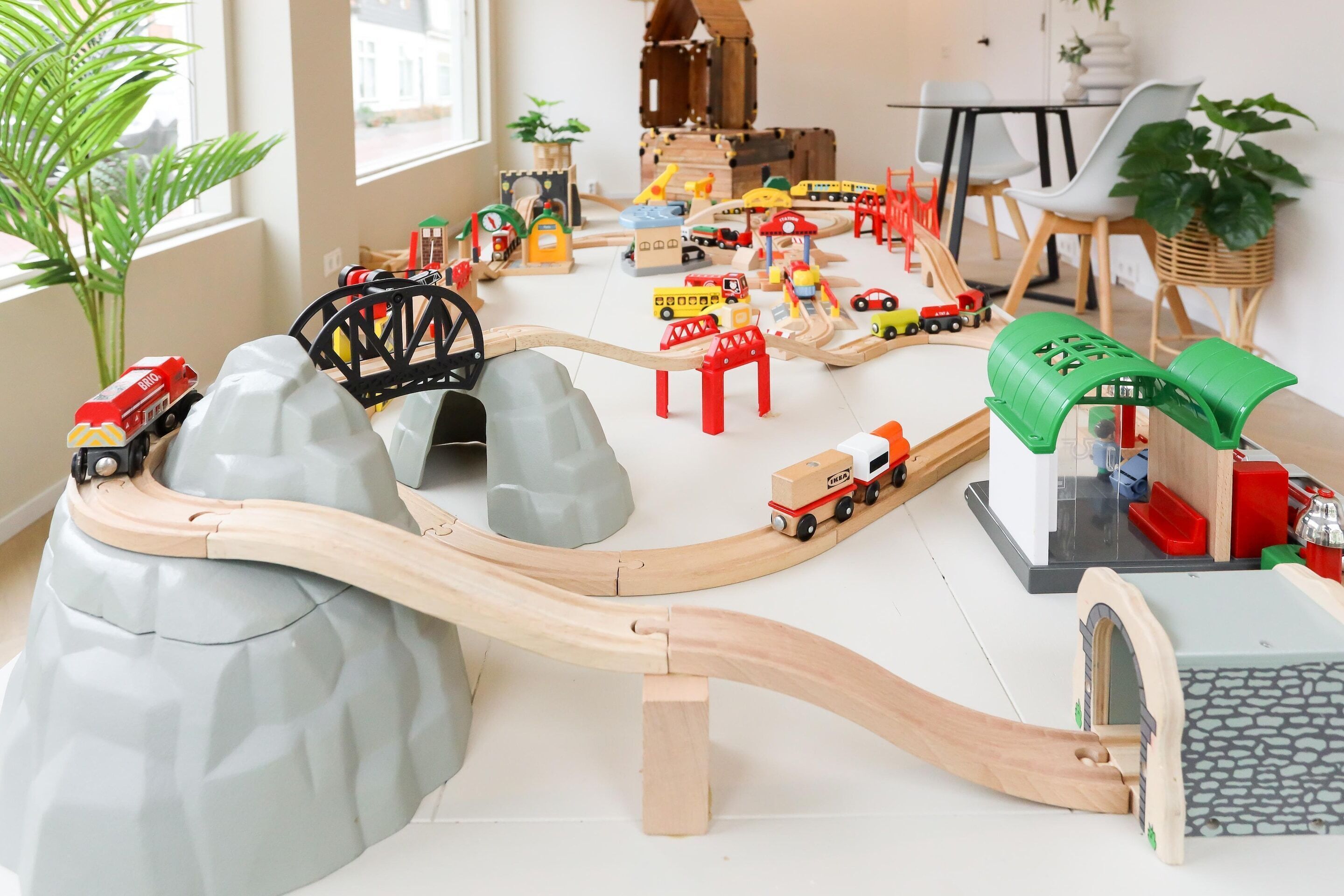 Un ensemble de jouets comprenant un train, des rails, des véhicules et des bâtiments.