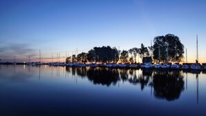 A marina at dusk with calm waters reflecting the boats and trees. - Unterkunft in Monkebude mit Eigenem Garten (Monkebude)