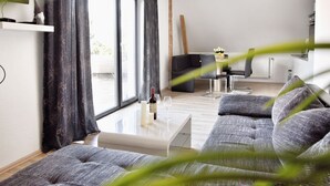 A modern living room with a sofa, coffee table, and a dining area with a table and chairs. - Unterkunft in Monkebude mit Eigenem Garten (Monkebude)