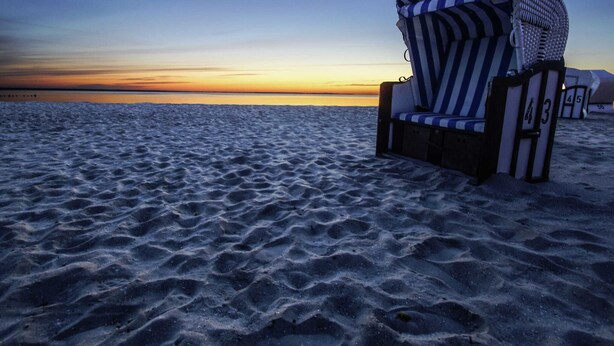 A beach chair with a striped cover, positioned on the sand near the water's edge. - Unterkunft in Monkebude mit Eigenem Garten (Monkebude)