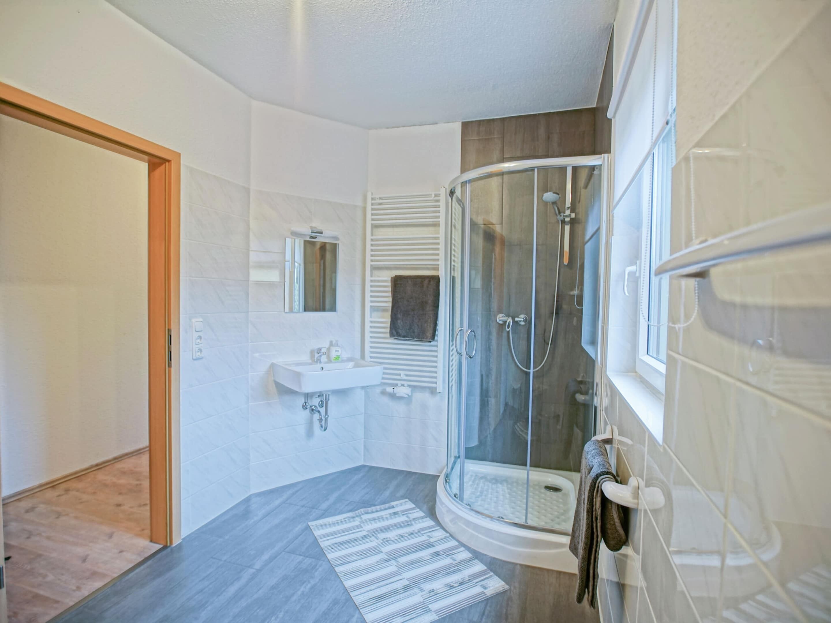 Ein modernes Badezimmer mit einer Duschkabine aus Glas, einem Waschbecken und einem Handtuchhalter.