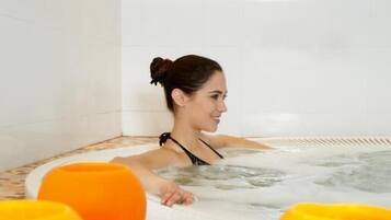Una persona en un jacuzzi con sillas flotantes anaranjadas, rodeado de piso de cerámica.