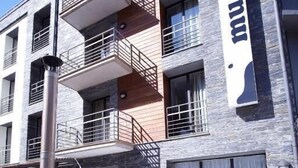 A wooden hot tub in front of a building with balconies and a sign that reads "hotel". - Hotel Mu (La Cortinada)