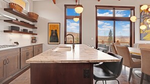 Una cocina con una isla grande, armarios de madera y vistas al exterior a través de amplios ventanales.