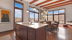 Una cocina moderna con una isla grande, vigas de madera y amplios ventanales con vistas al exterior.