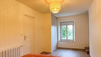 A bedroom with a bed, a window, and a ceiling light fixture.