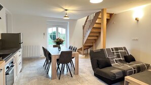 Een moderne keuken met een eethoek, een trap en een woonkamer met een bank en een salontafel.