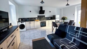 Een moderne keuken met een inbouwoven, een wasmachine en een zithoek met een bank en tafel.