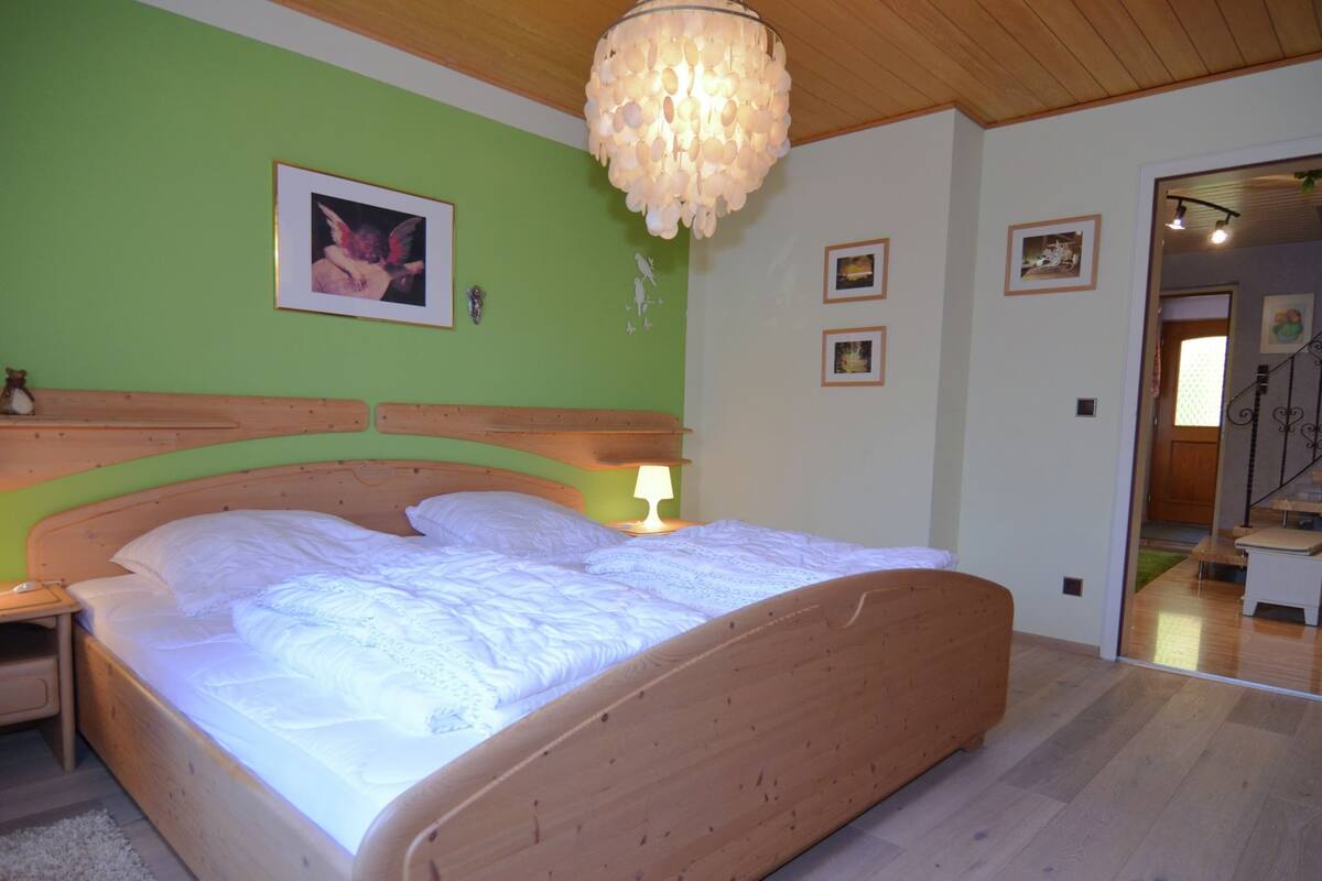 Un dormitorio con una cama de madera, una mesita de noche, una lámpara y un candelabro.