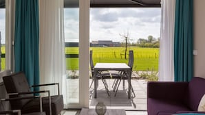 A modern living room with a view of a green field through large glass doors. - Luxury Apartment With sun Shower at the Edge of the Beautiful Oostkapelle (Oostkapelle)