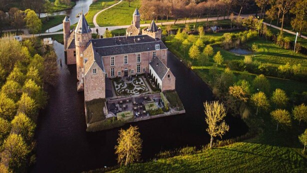 A castle with a moat, surrounded by lush greenery and a river. - Luxury Apartment With sun Shower at the Edge of the Beautiful Oostkapelle (Oostkapelle)
