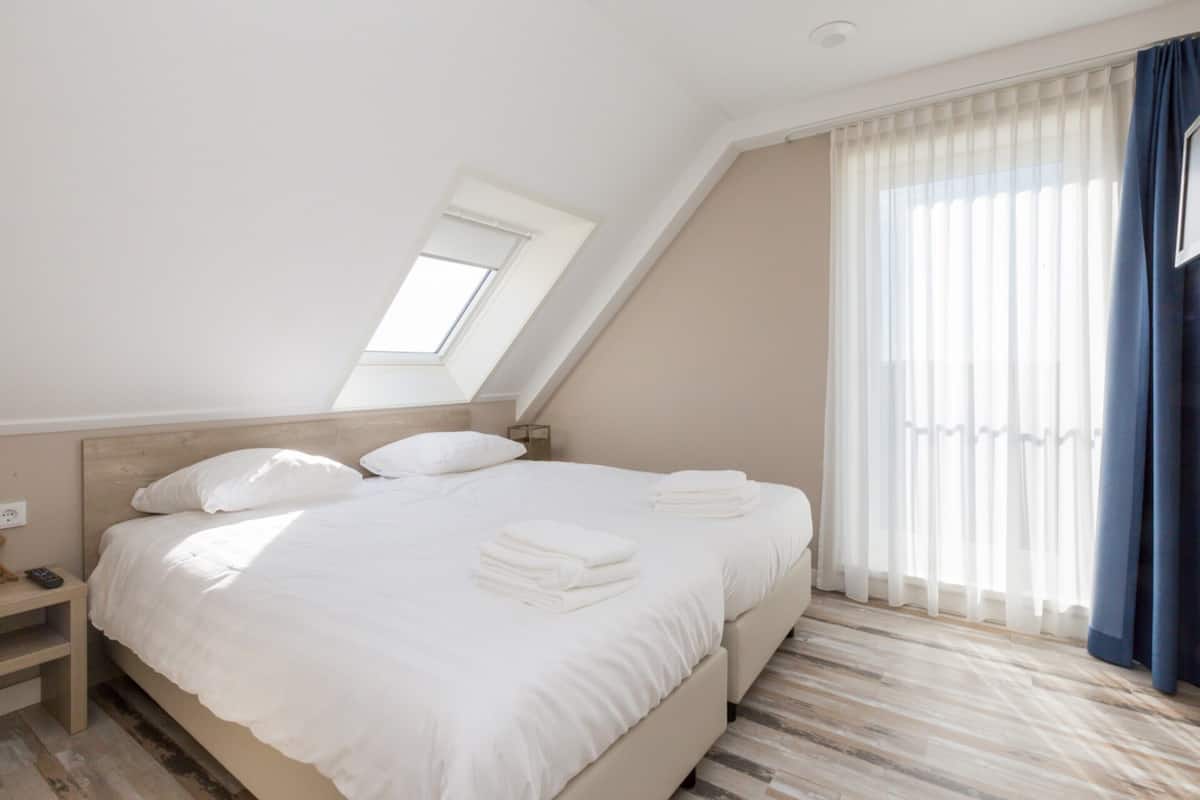 Une chambre à coucher moderne avec un grand lit, une table de chevet et une lucarne.