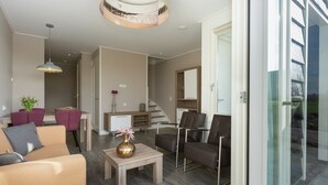 A modern living room with a sofa, chairs, a coffee table, and a dining area with chairs and a table. - Luxury Apartment With sun Shower at the Edge of the Beautiful Oostkapelle (Oostkapelle)