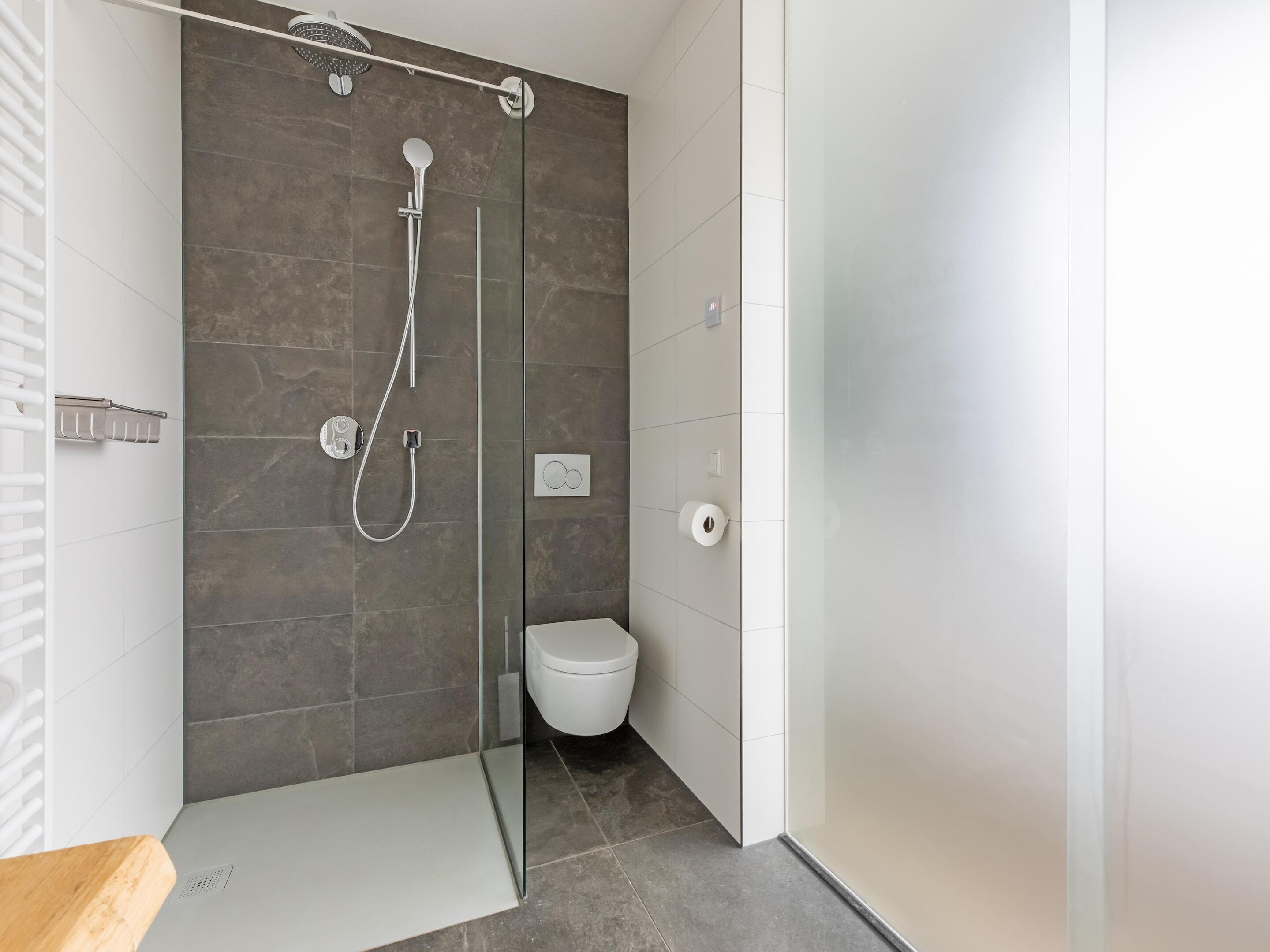 A modern bathroom with a glass-enclosed shower, a white toilet, and a wooden countertop.